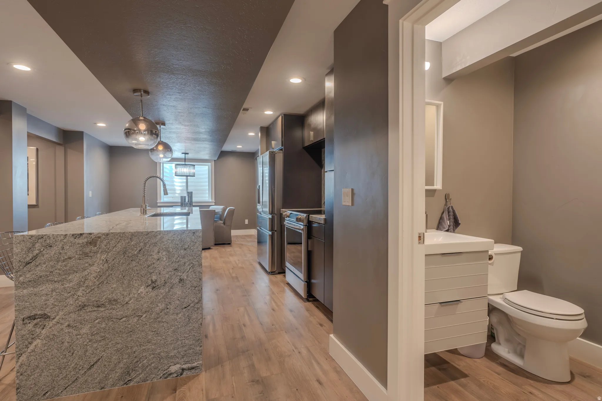Expansive kitchen island with a stone countertop, featuring a gooseneck faucet and pendant lighting