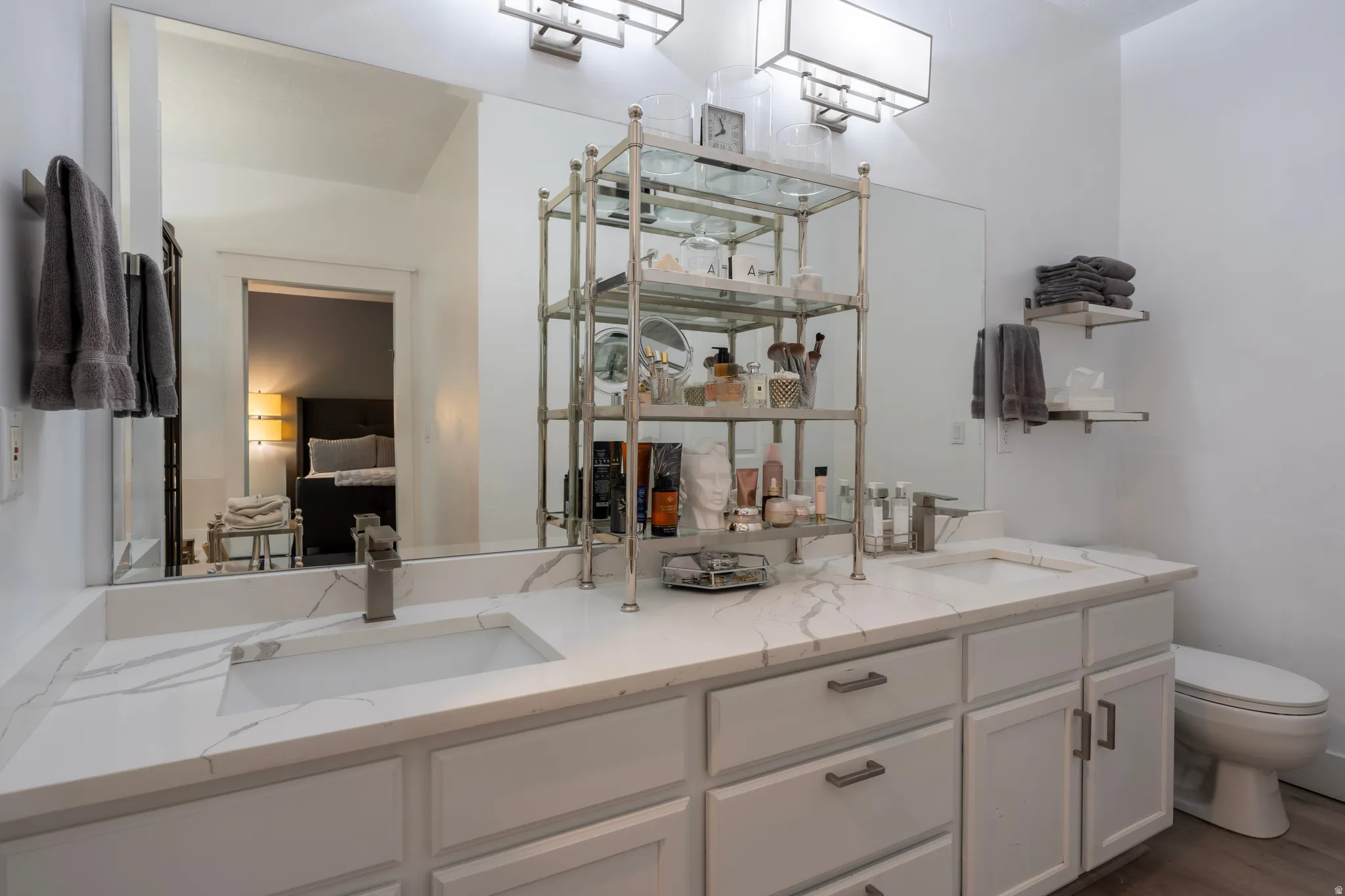 Dual undermount sinks with brushed nickel faucets, white cabinetry, and white countertops featuring gray veining