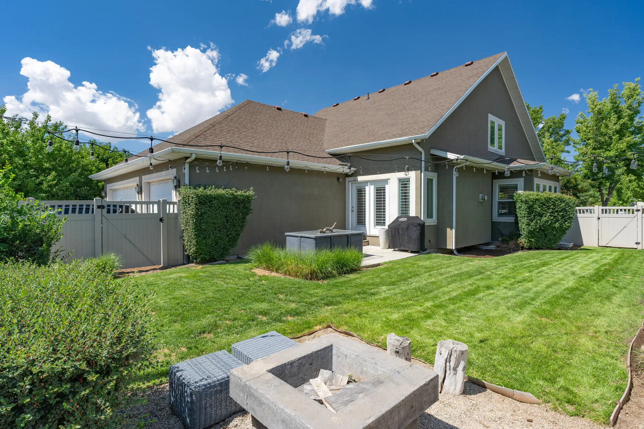 Expansive backyard featuring a manicured lawn, established landscaping, and a concrete fire pit