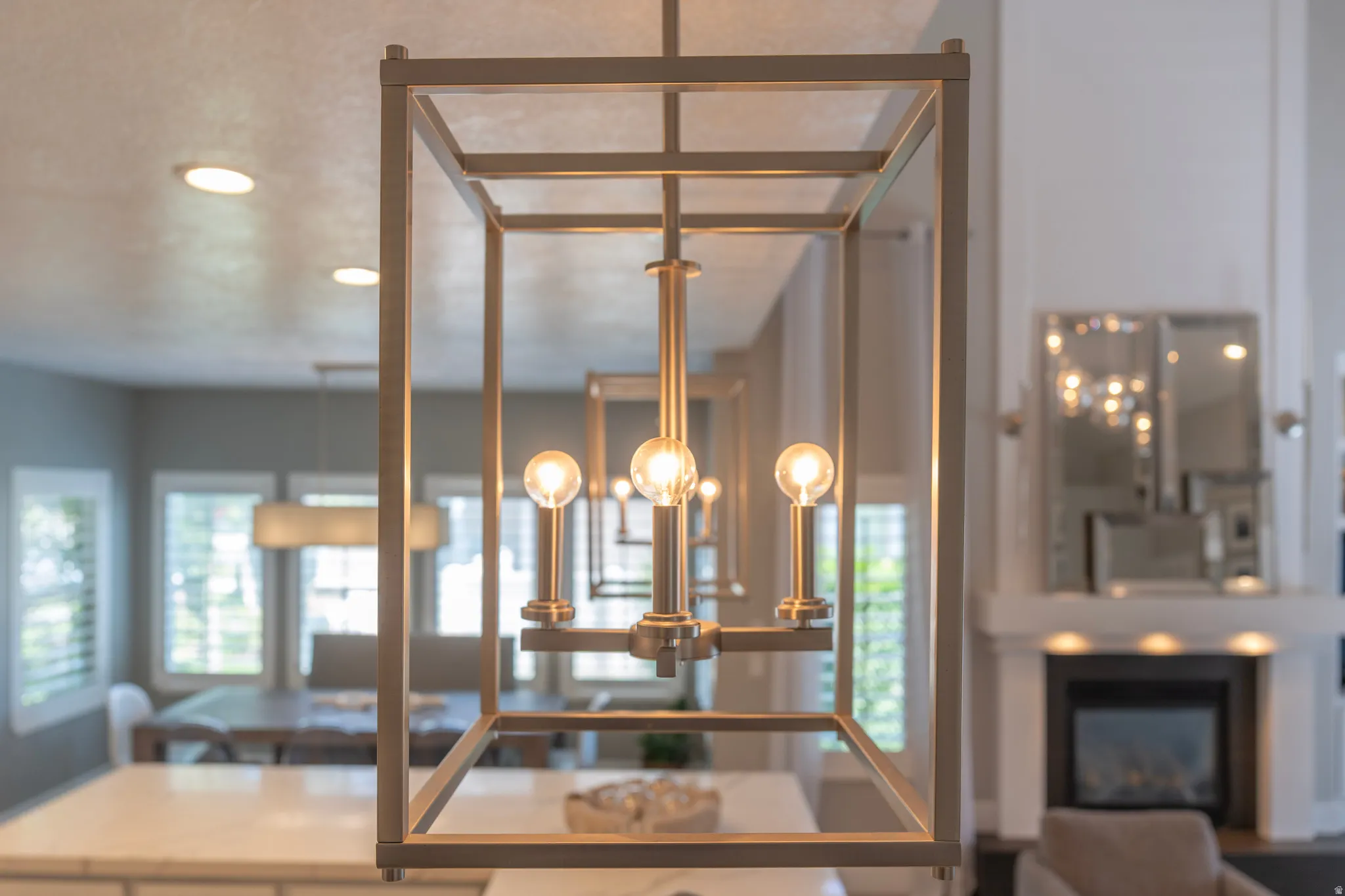 Recessed lighting, contemporary linear chandelier, white countertop, white fireplace surround, and built-in fireplace