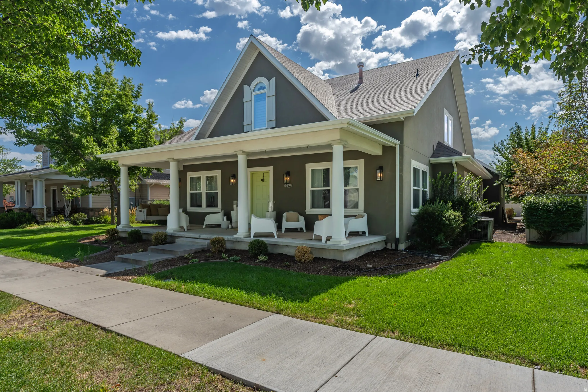 Gable roofline, covered front porch, decorative front door, mature landscaping, and an arched window with shutters