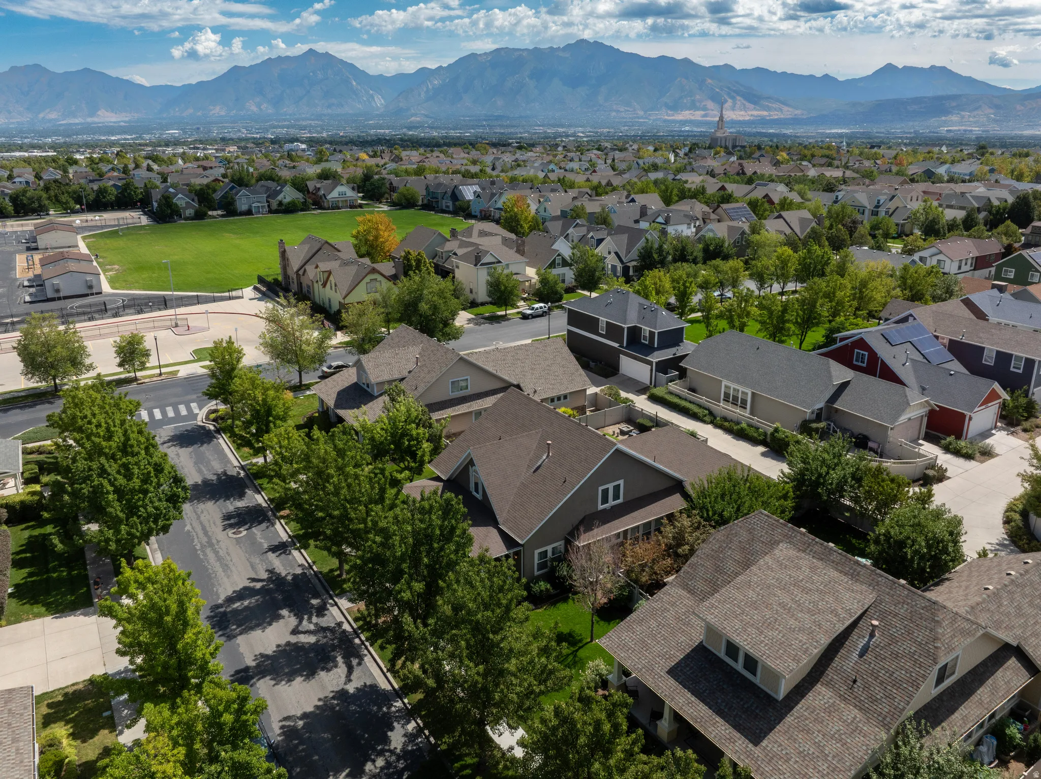 Residential neighborhood with mature trees, mountain backdrop, and common green space