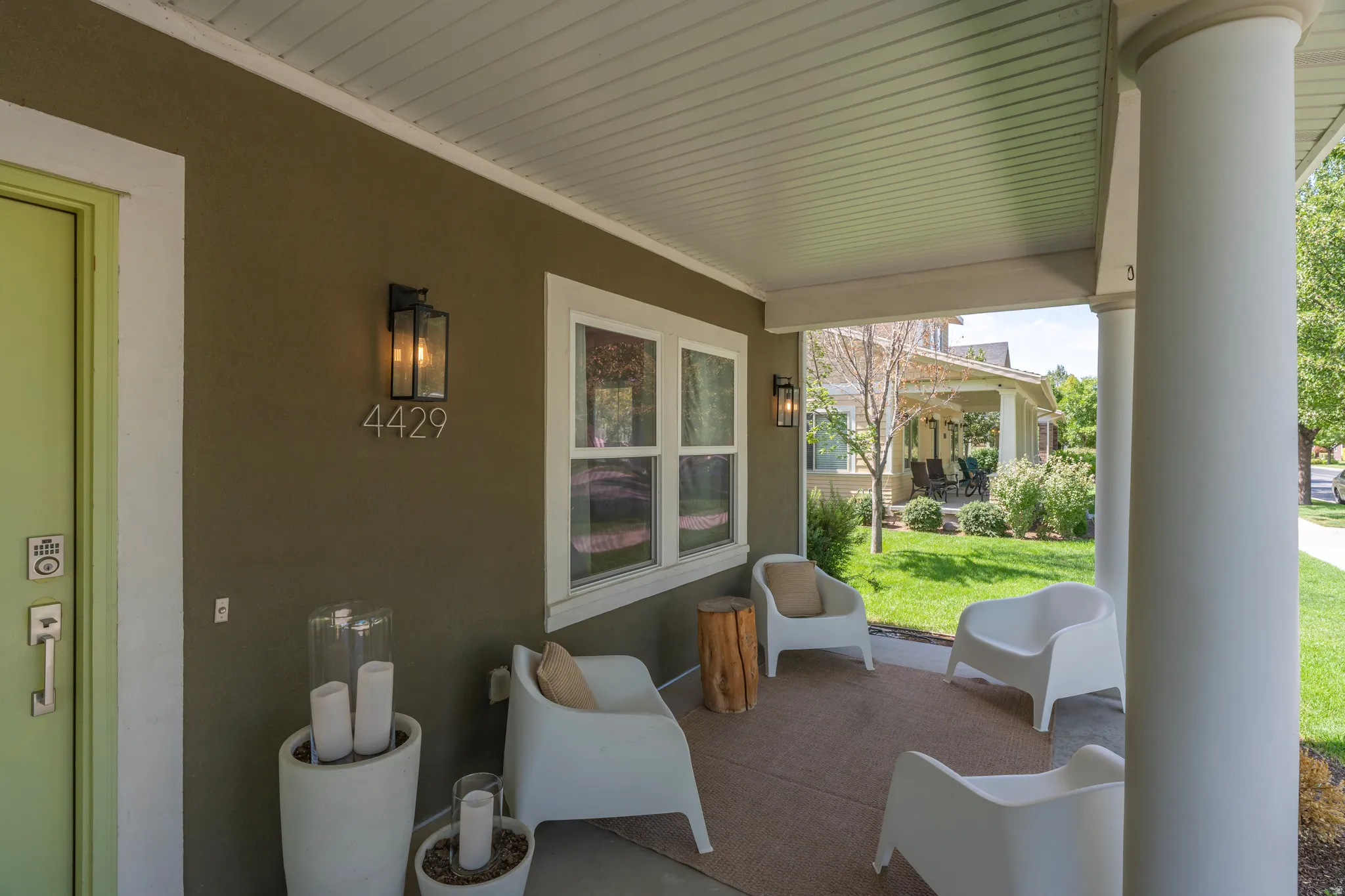 Covered front porch with substantial columns, a light-colored entry door, and exterior wall lanterns