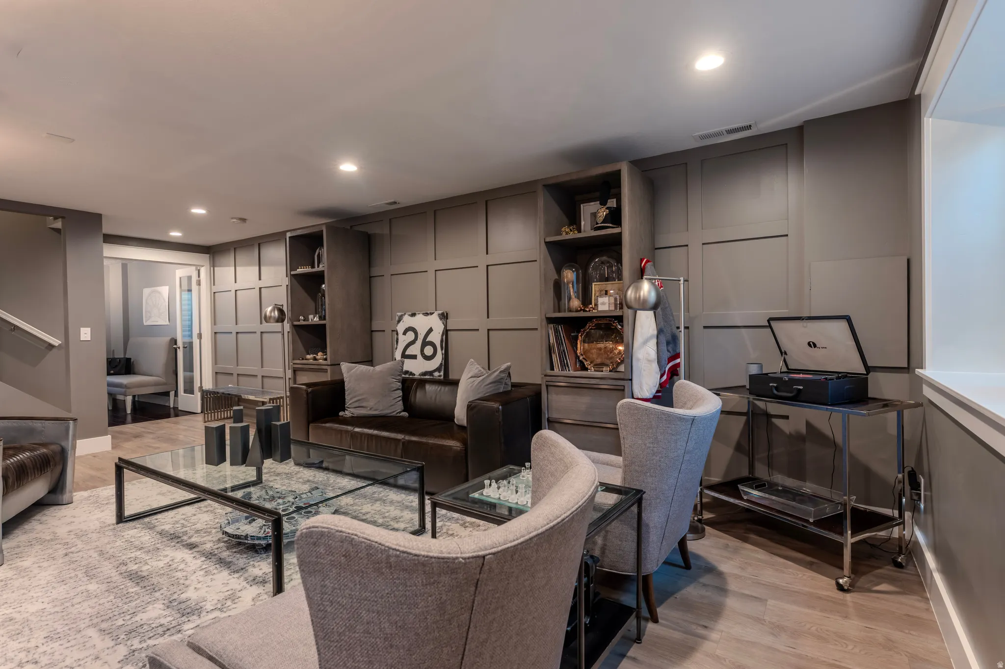 Built-in shelving, recessed ceiling lighting, wood-finish flooring, accent paneling, and an egress window