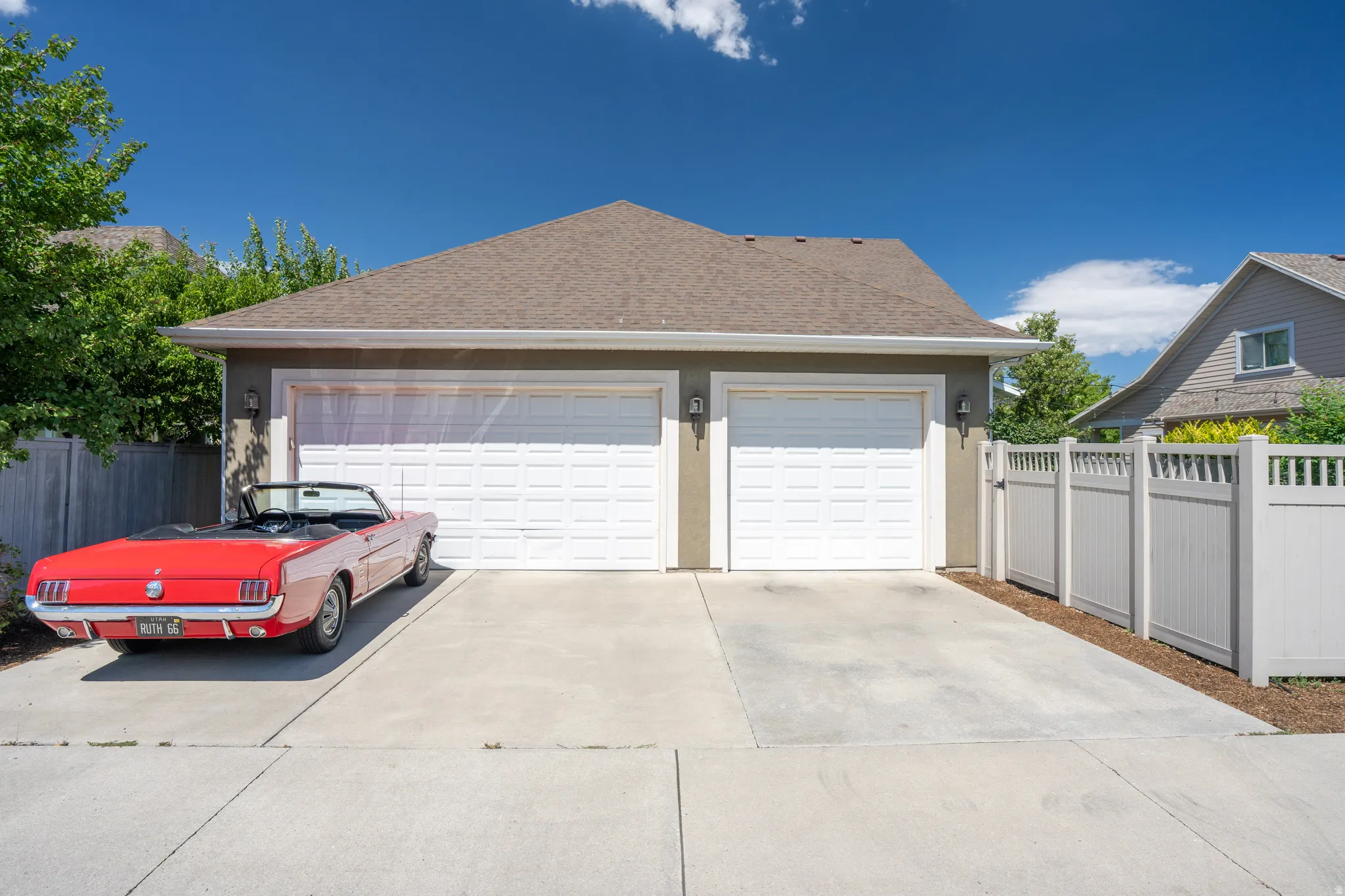 Two-car garage with white panel doors and exterior sconce lighting