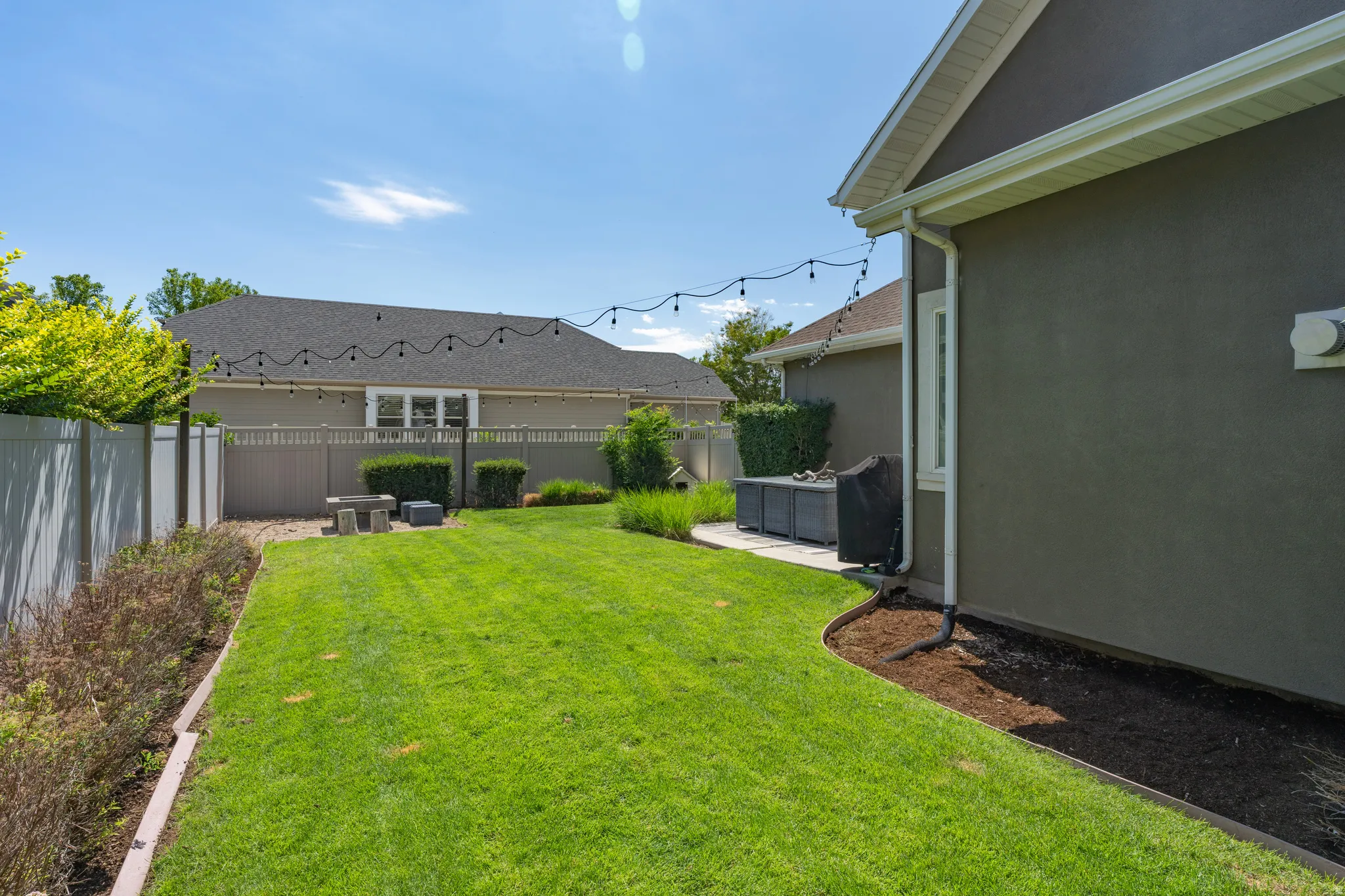 Expansive backyard featuring a manicured lawn, concrete patio, and perimeter fencing