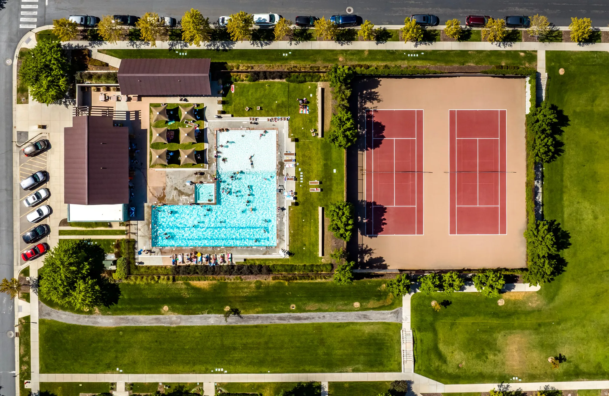 Community recreation area featuring an expansive swimming pool, adjacent wading pool, and two full-size tennis courts