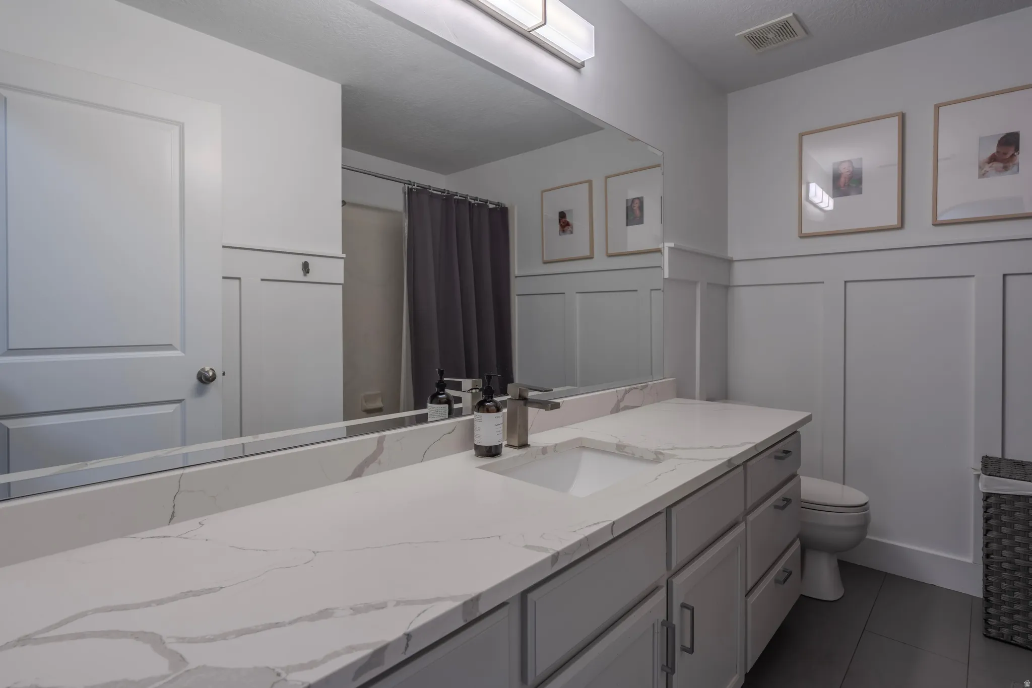 Extended vanity with an integrated rectangular sink, stone-finish countertop, and wall-mounted light fixture