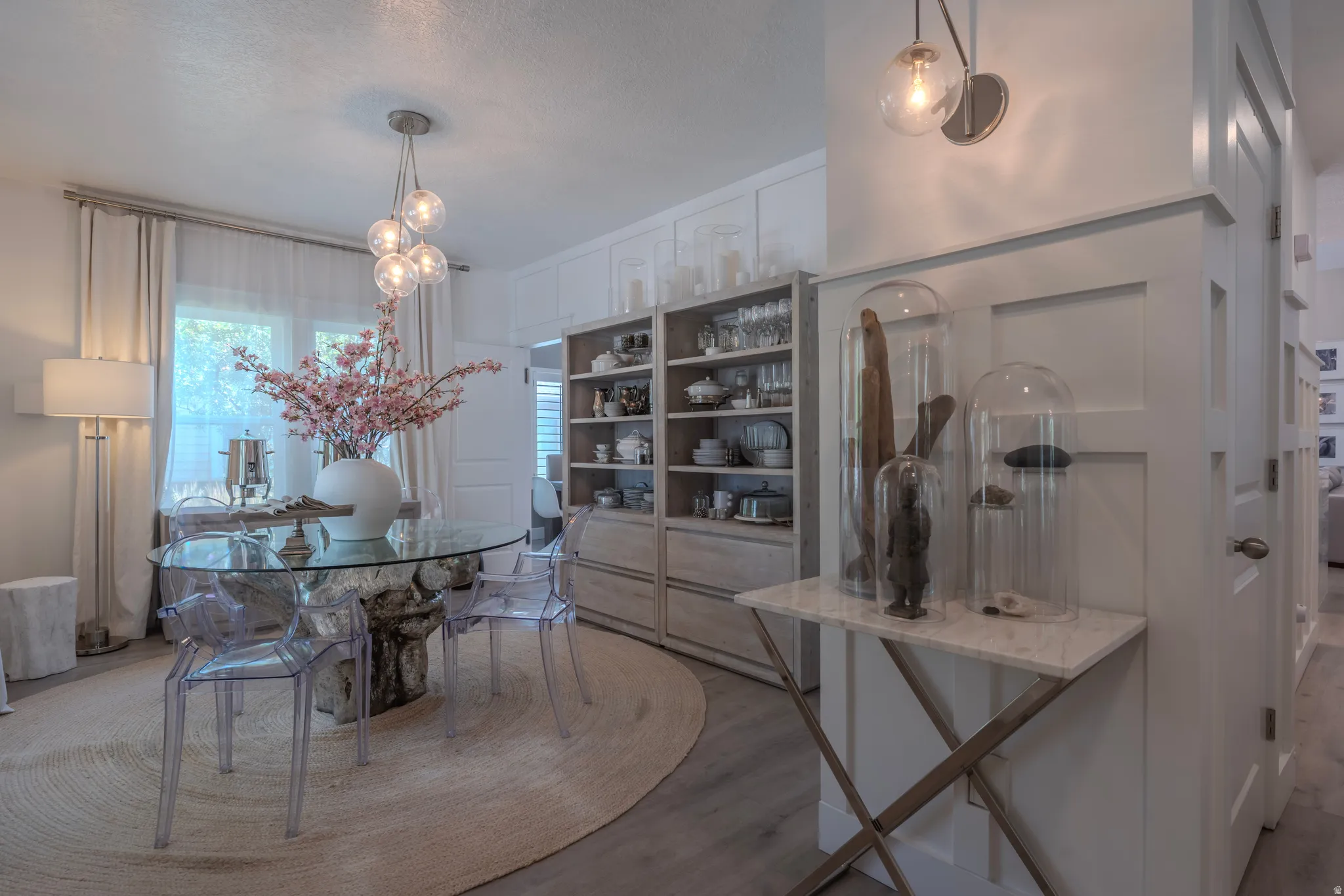 Dining area featuring a contemporary glass chandelier, a glass-top table with a unique base, and built-in shelving with lower cabinet storage