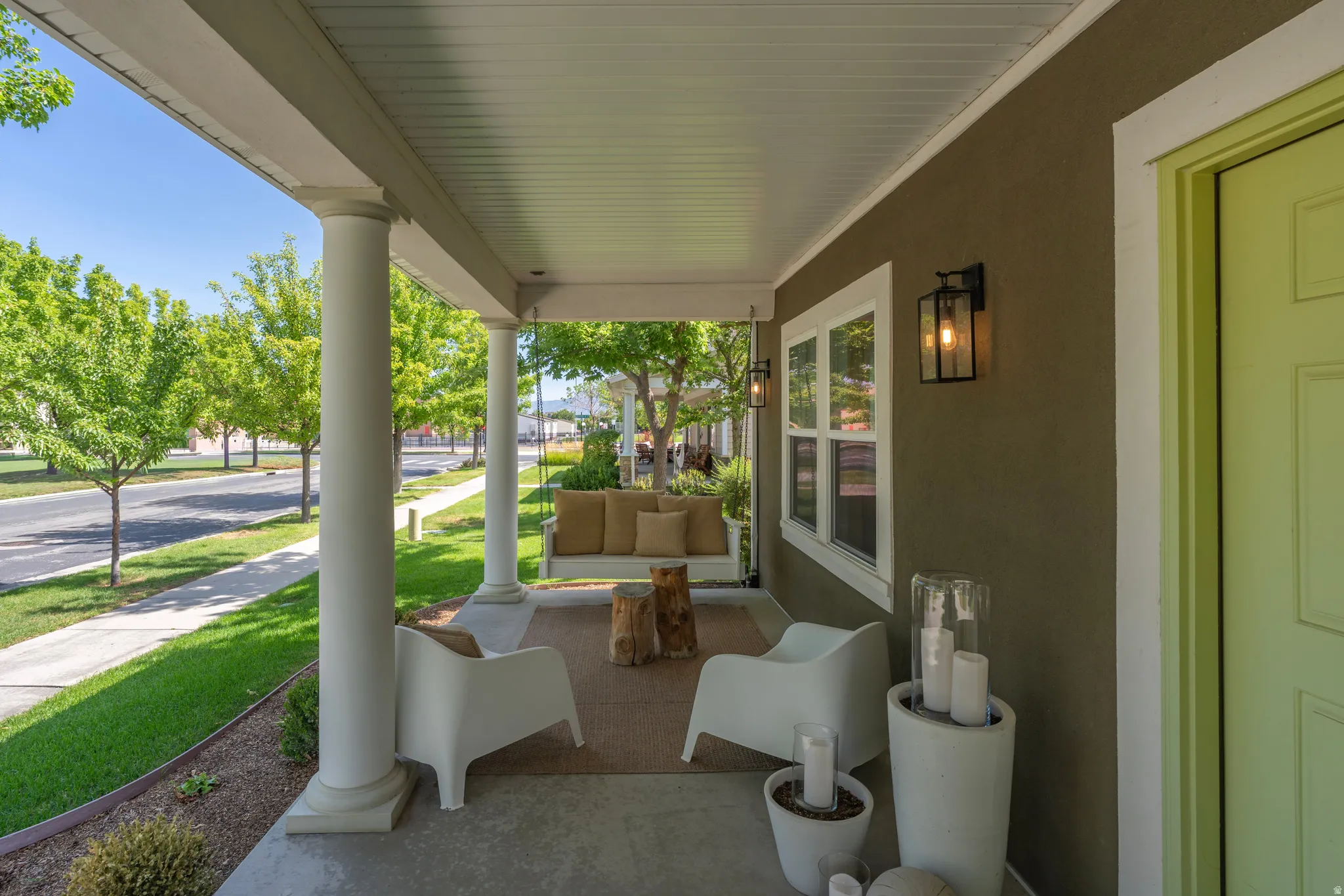 Expansive covered front porch with multiple pillars, stucco exterior, and a brightly colored entry door