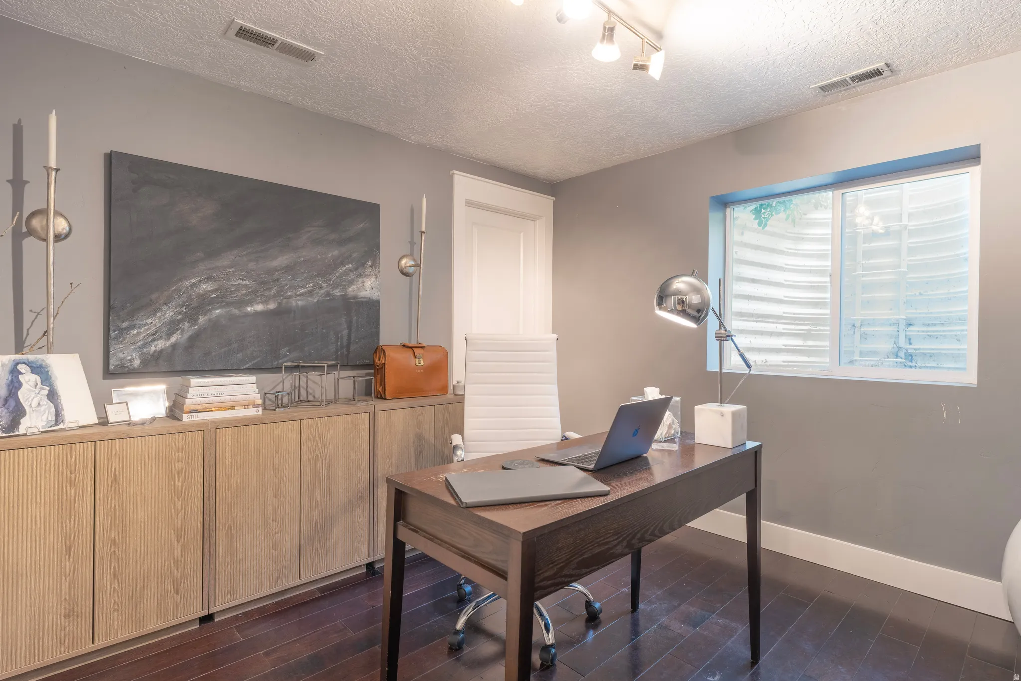 Recessed lighting, wood-finish flooring, light wood-tone built-in cabinetry, painted walls, and a window with a well