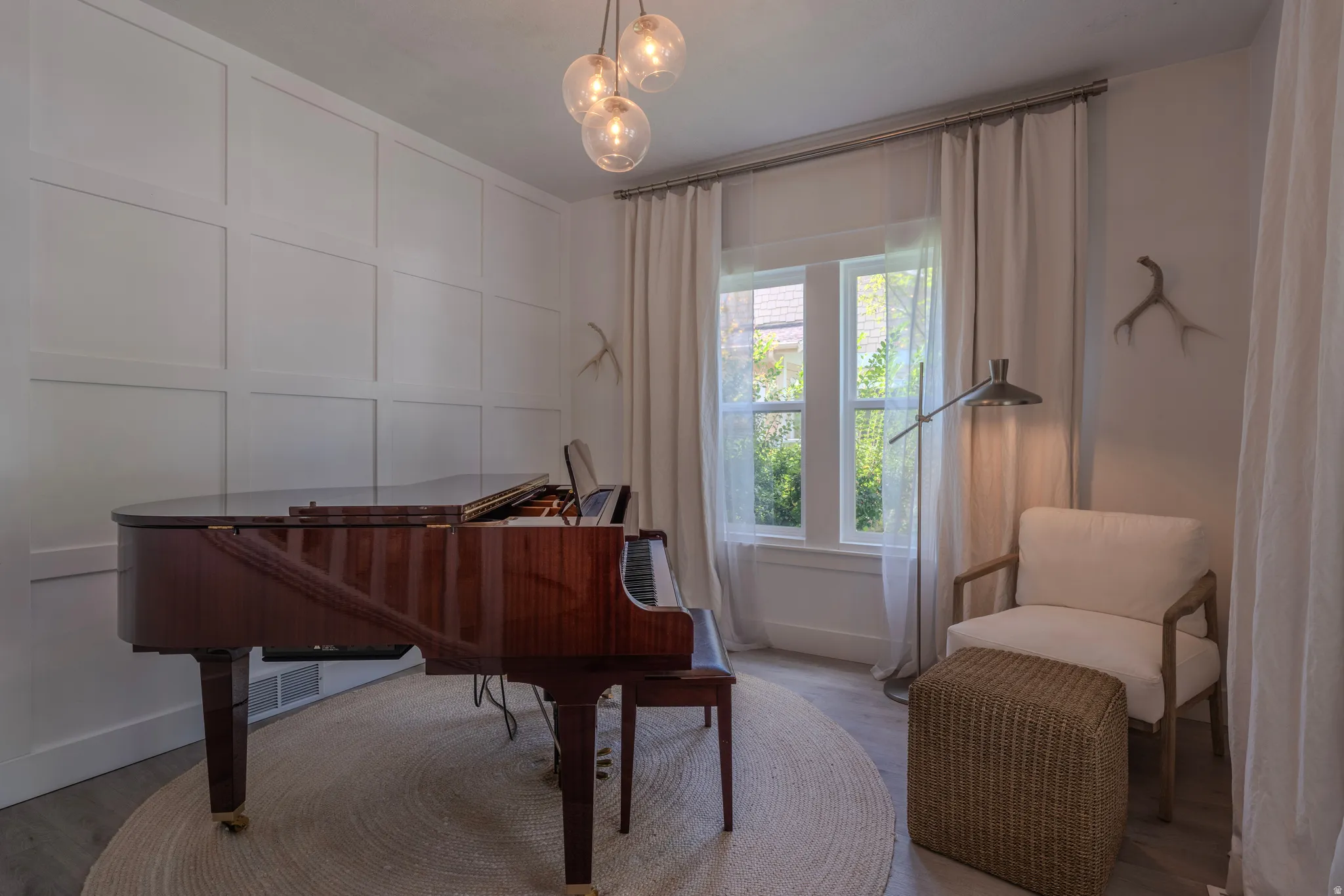 Board and batten wall paneling, multi-pane window, suspended globe lighting fixture, wood-finish flooring, and full-height window treatments