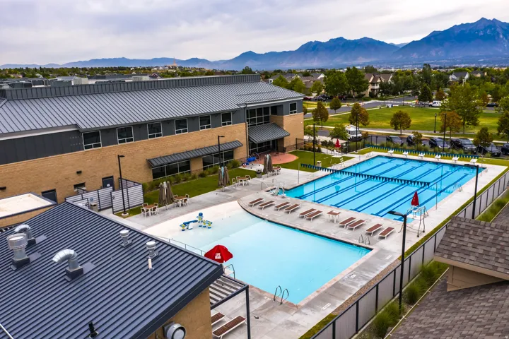 Expansive community pool area featuring a multi-lane lap pool, a separate recreation pool, and a surrounding concrete deck