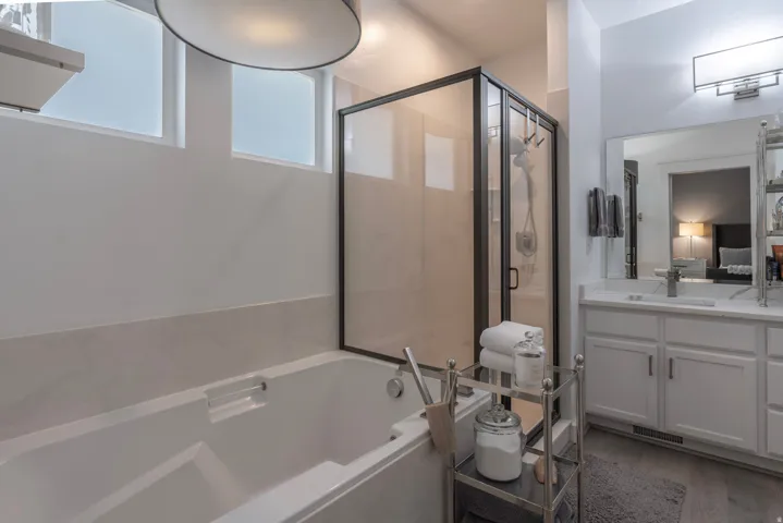 Freestanding soaking tub with a glass-enclosed shower, dual vanity with undermount sinks, and tiled flooring