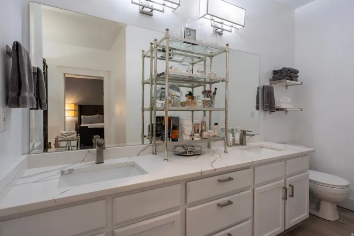 Dual undermount sinks with brushed nickel faucets, white cabinetry, and white countertops featuring gray veining