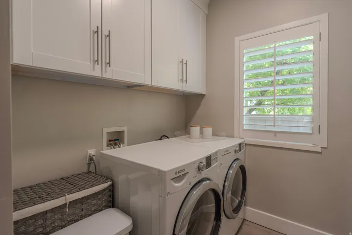 White shaker-style cabinetry with brushed nickel hardware and a window with plantation shutters