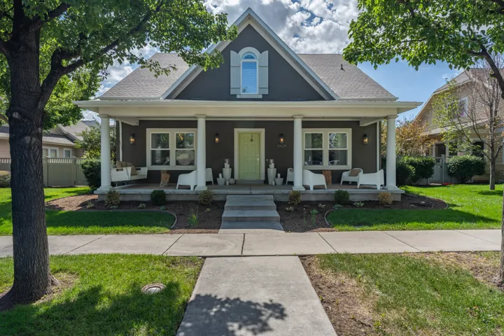 Craftsman-style exterior with a covered front porch, prominent dormer window, and mature trees