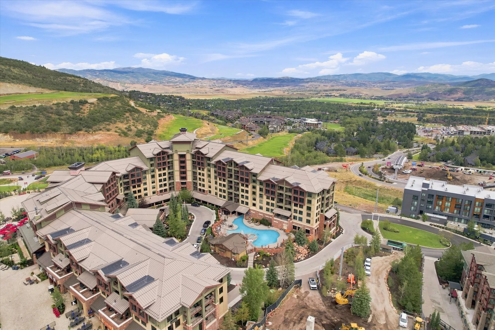 Expansive resort-style development featuring multiple buildings, an outdoor pool with rock features, and surrounding mountain scenery