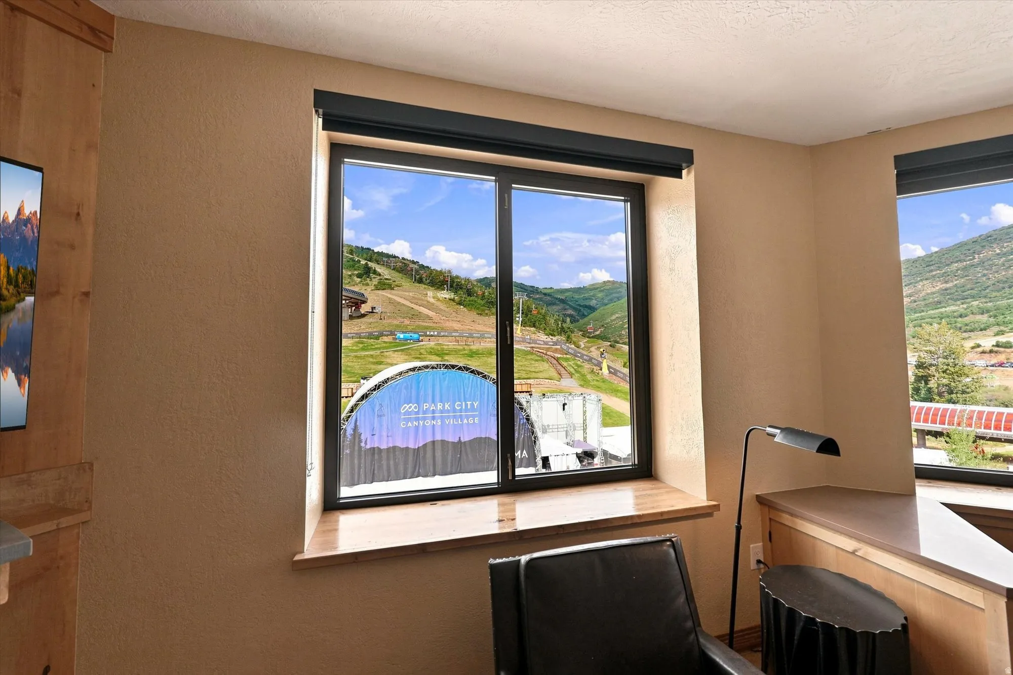 Dual windows with natural wood sills, black window frames, and exterior mountain scenery