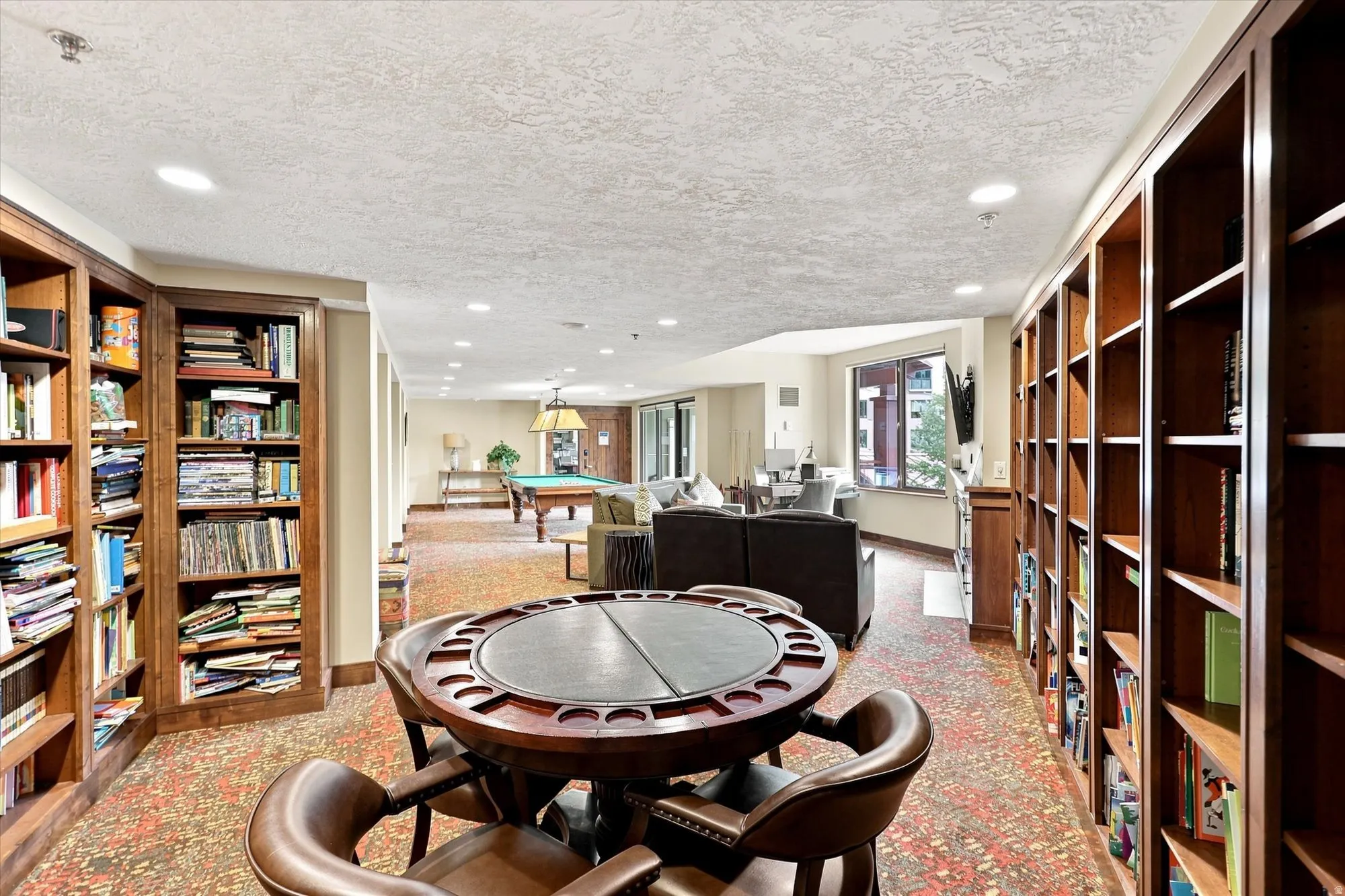 Expansive common area featuring extensive built-in bookcases, recessed lighting, and large windows