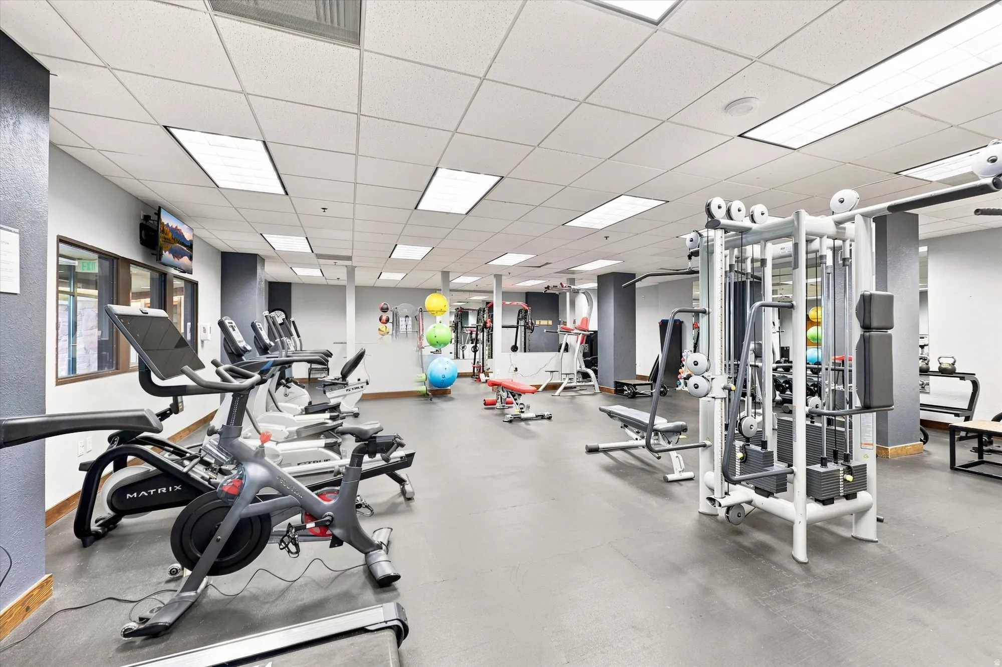 Fitness center with multiple exercise machines, weight equipment, and a mounted television
