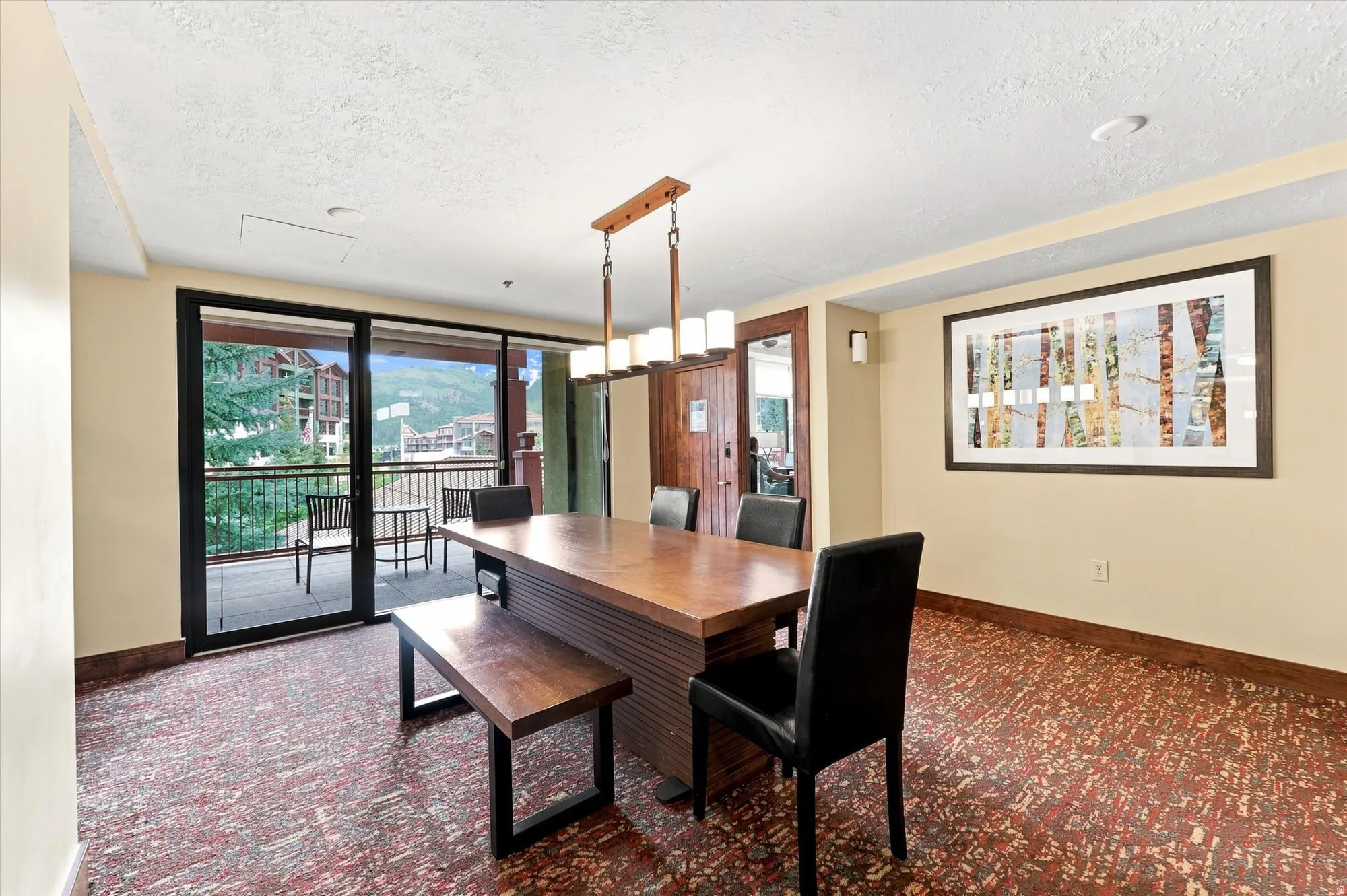 Sliding glass doors opening to a private balcony, wood-finish flooring, recessed lighting, and a pendant light fixture