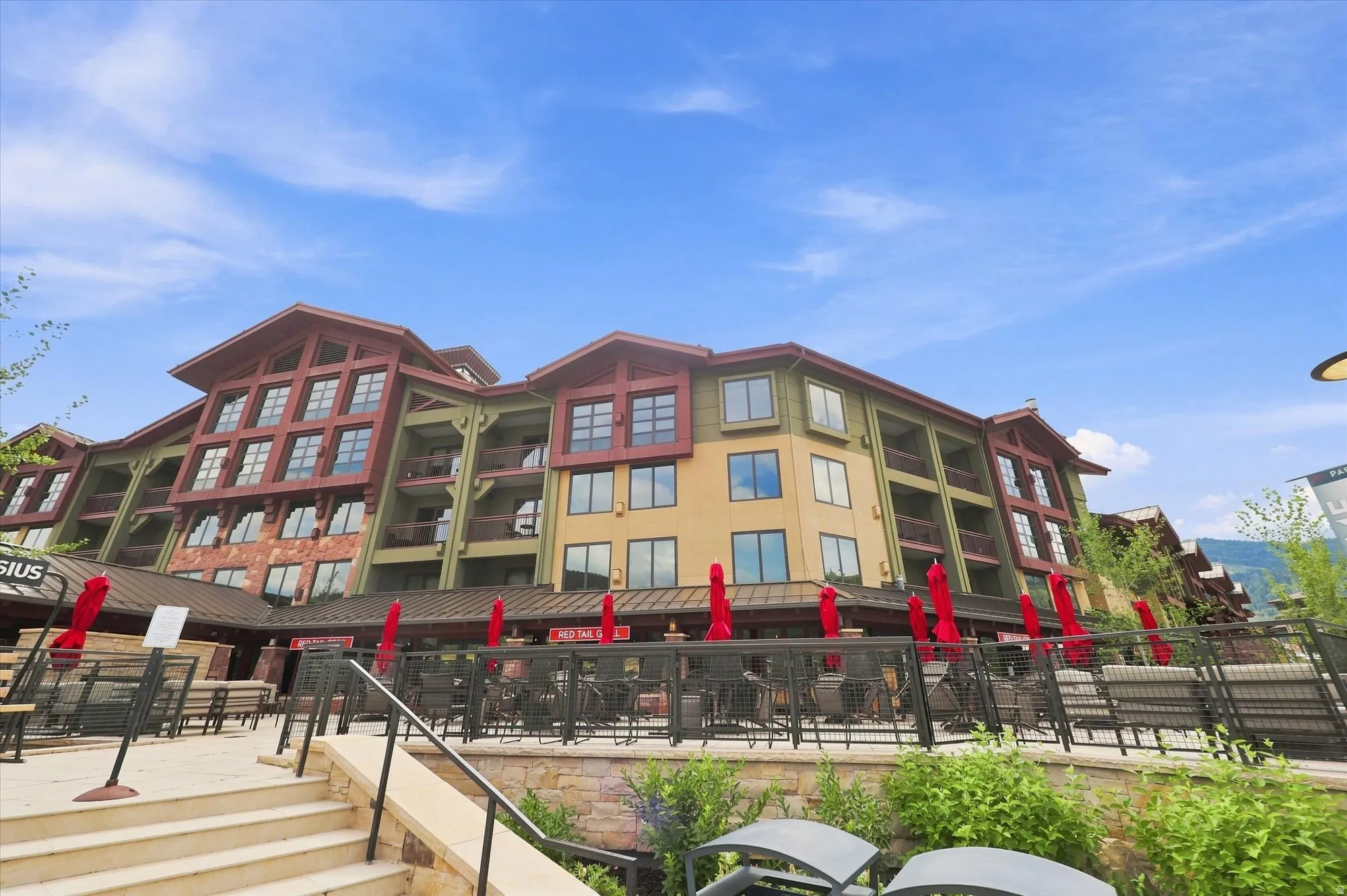 Multi-story building featuring warm-toned exterior siding, multiple balconies, and a stone-clad base