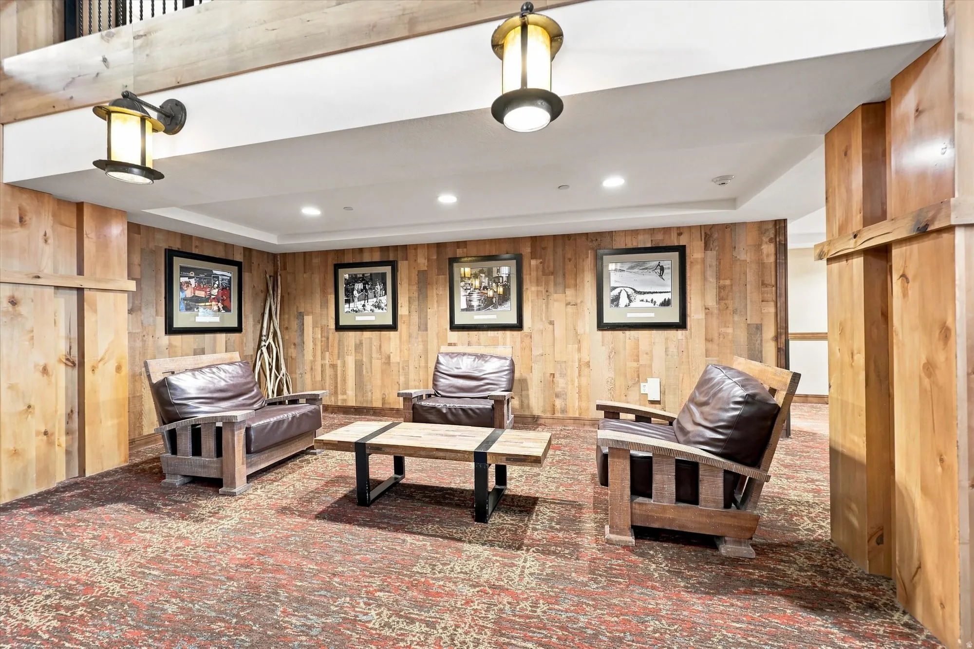 Finished basement recreation room featuring warm wood-paneled walls, recessed and pendant lighting, patterned area rug, and built-in wood cabinetry