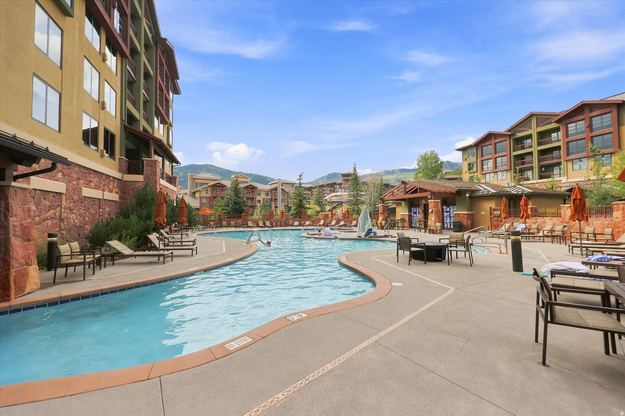 Expansive outdoor pool with integrated spa, concrete deck, and surrounding lounge areas