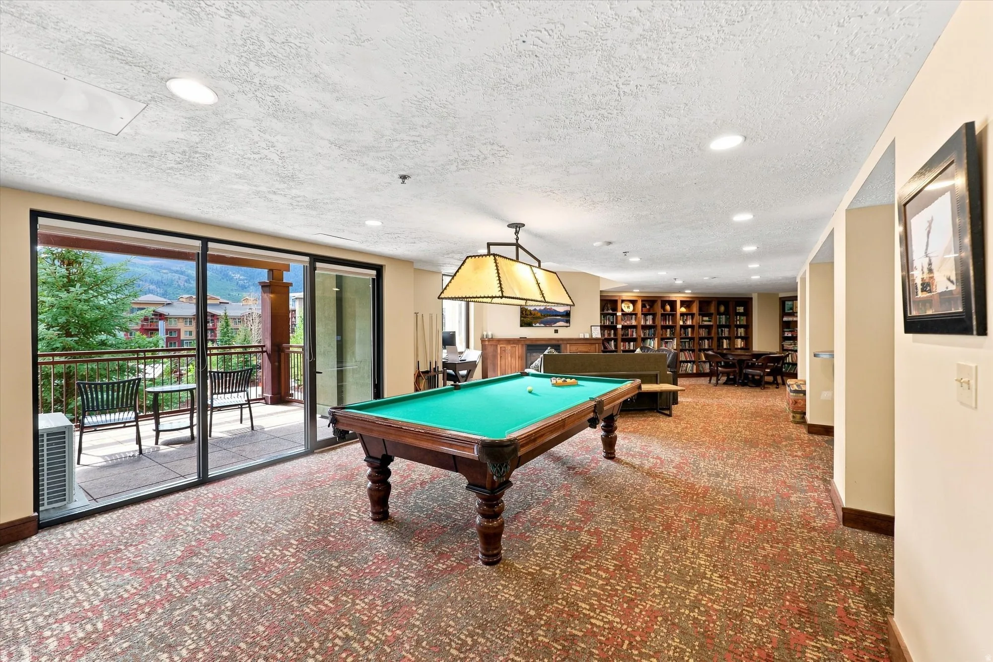 Spacious recreation area featuring a full-size billiard table, recessed lighting, and a private balcony with sliding glass doors