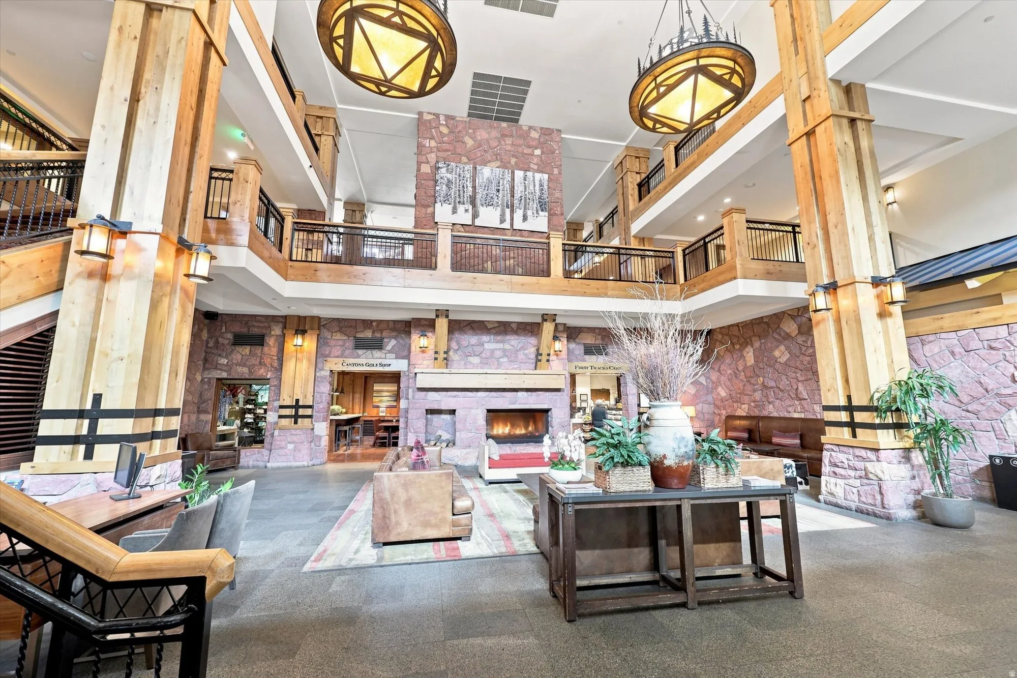 Spacious multi-level interior featuring exposed timber beams, a stone-clad fireplace, and wrought iron railings