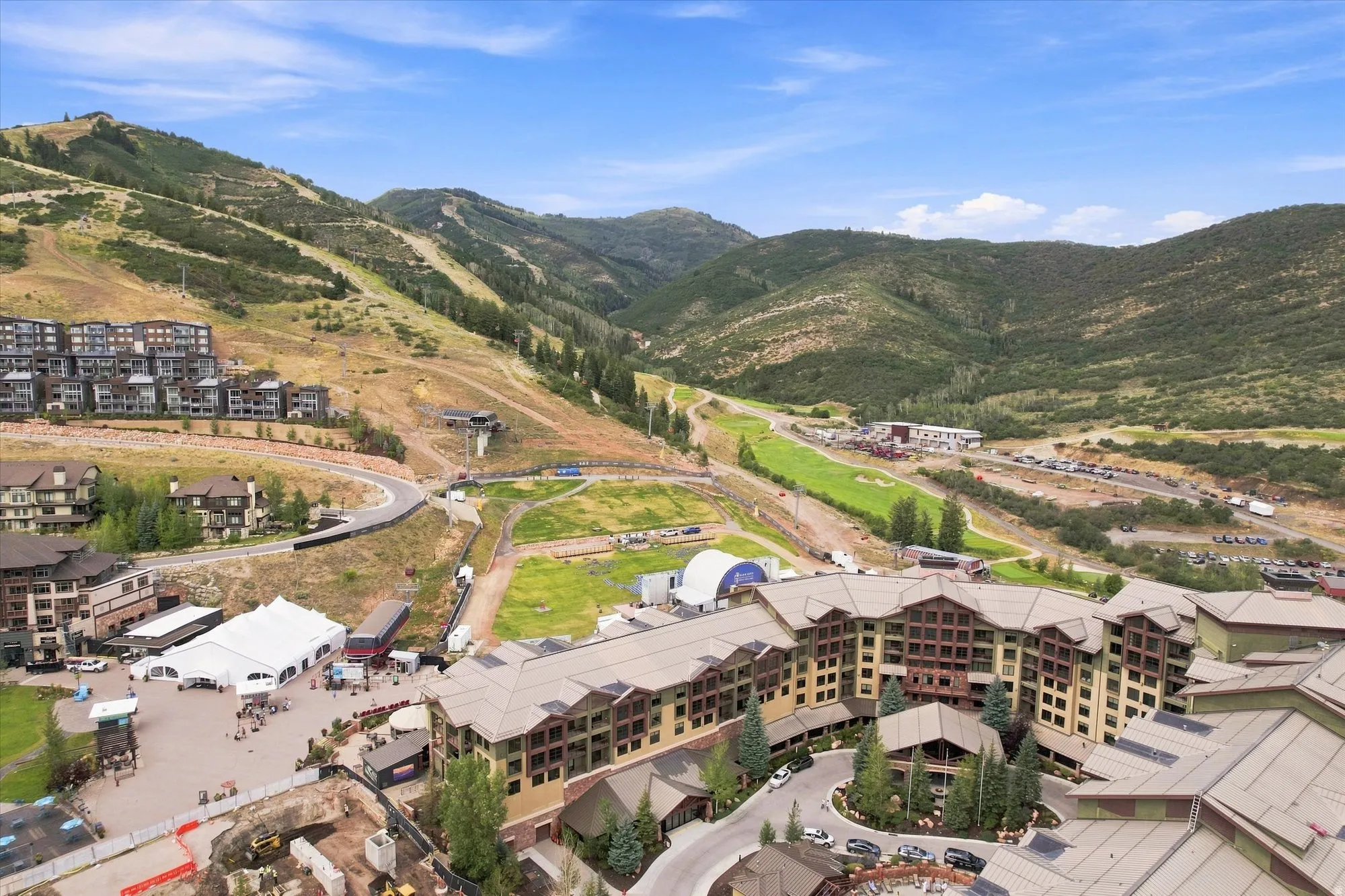 Mountainous terrain with lush greenery, multiple multi-story buildings with pitched roofs, terraced residential structures, and a paved circular drive