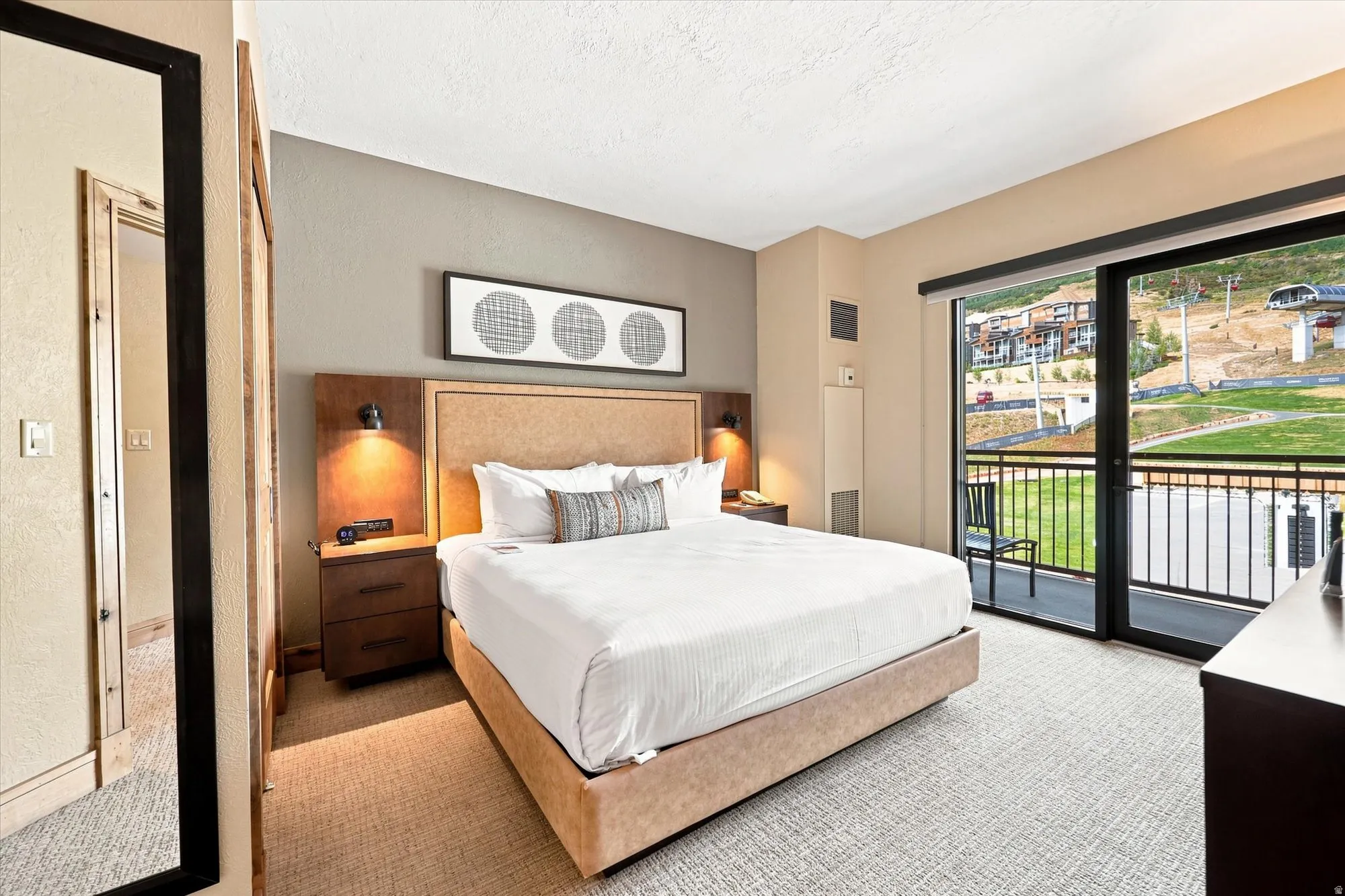 Carpeted bedroom with a built-in headboard and integrated wall sconces