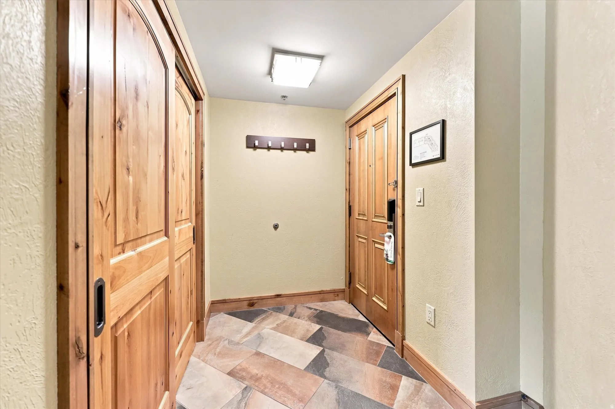 Entryway featuring wood-finish flooring, a paneled wood entry door, and a built-in coat rack