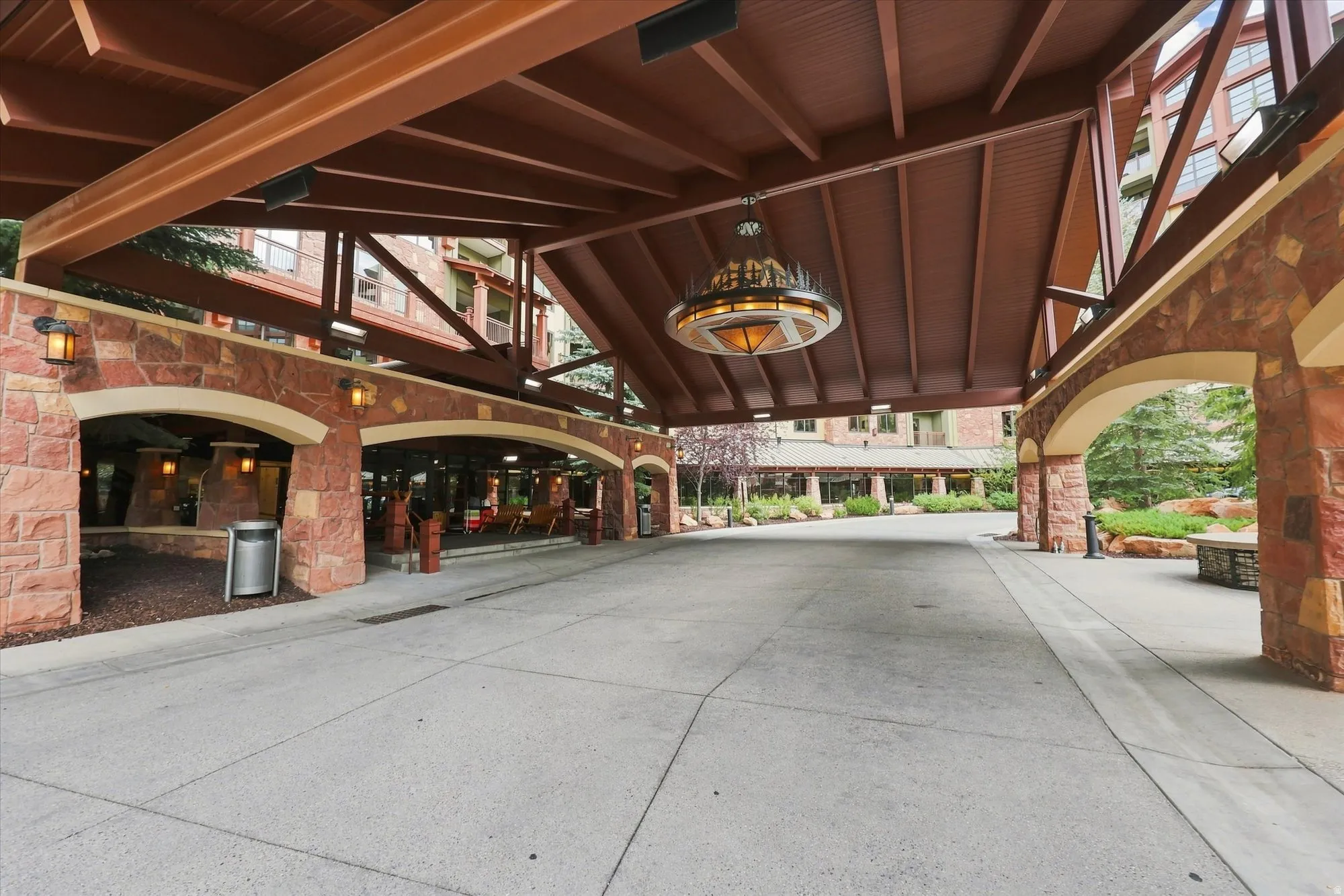 Stone facade with arched openings, wood-paneled porte-cochère, and a central decorative chandelier
