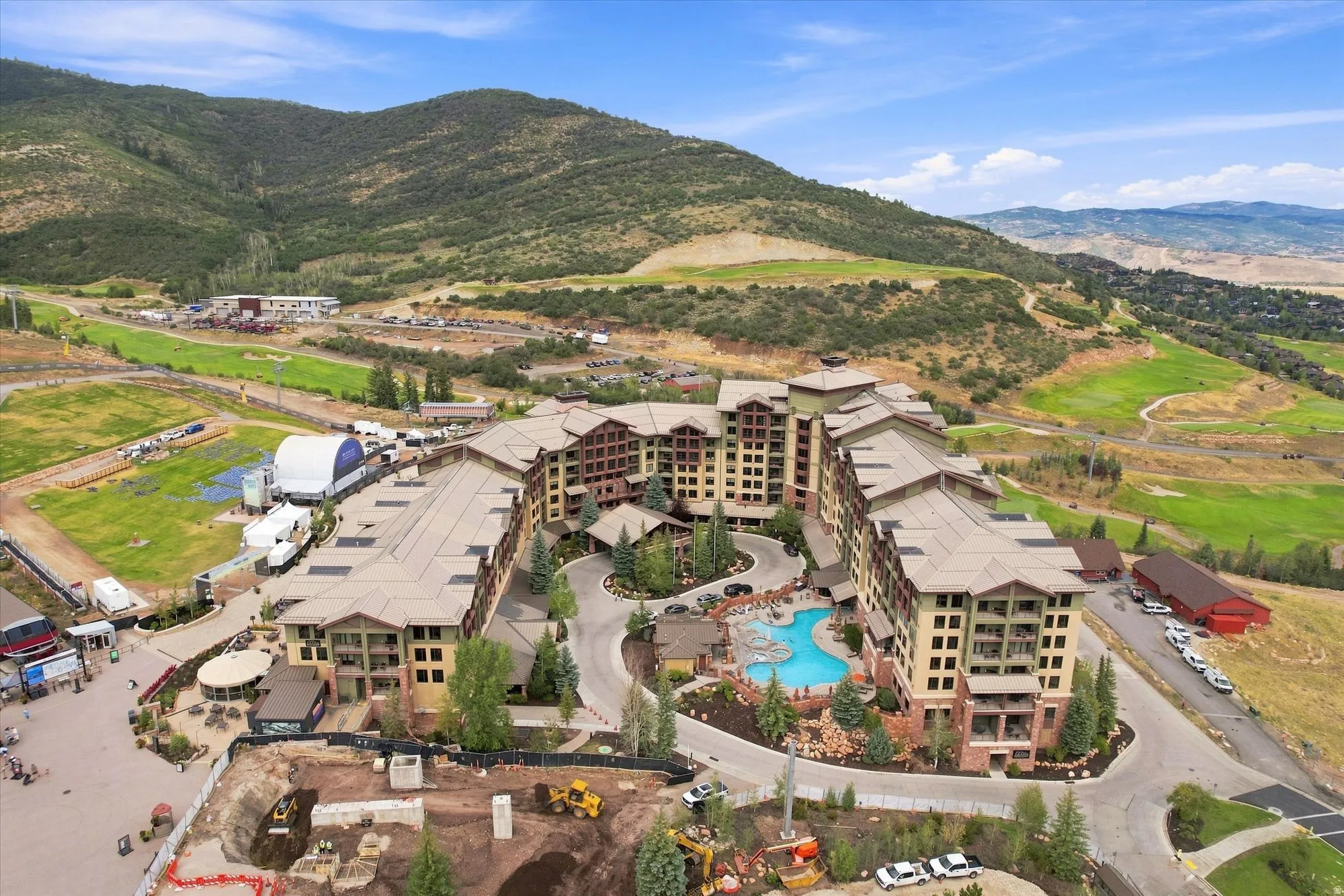 Multi-story residential complex featuring multiple buildings, an outdoor pool with rock landscaping, and surrounding mountainous terrain