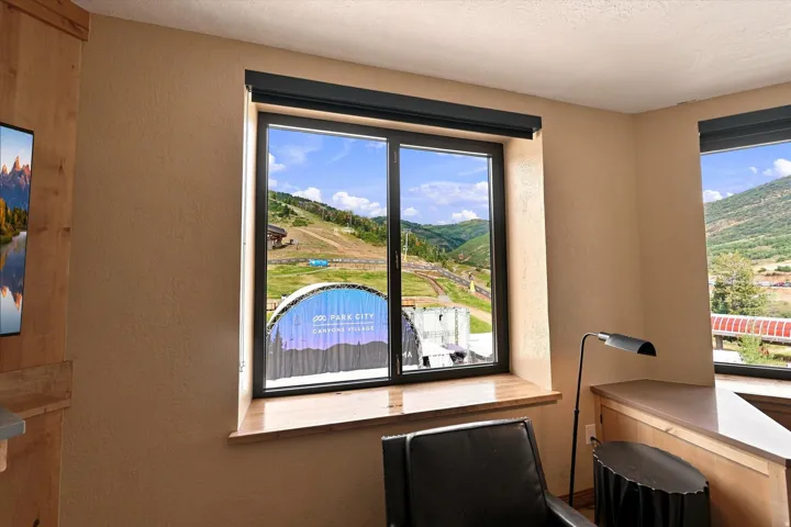 Dual windows with natural wood sills, black window frames, and exterior mountain scenery
