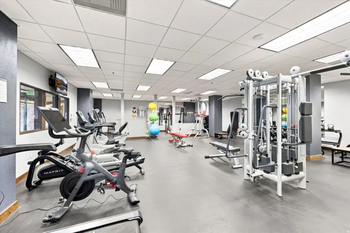 Fitness center with multiple exercise machines, weight equipment, and a mounted television