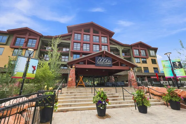 Multi-story property featuring a stone and wood exterior, multiple balconies, and a covered main entrance