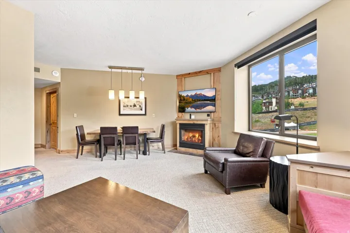 Spacious living area featuring a built-in fireplace, large windows, recessed lighting, and a dining area with a linear pendant light