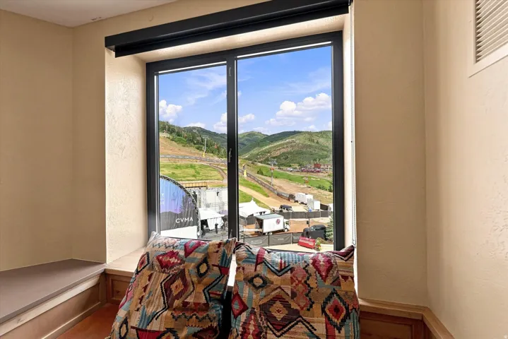 Expansive window with mountain scenery, integrated window seat with wood paneling, and a built-in wall niche