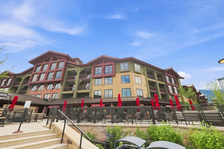 Multi-story building featuring warm-toned exterior siding, multiple balconies, and a stone-clad base