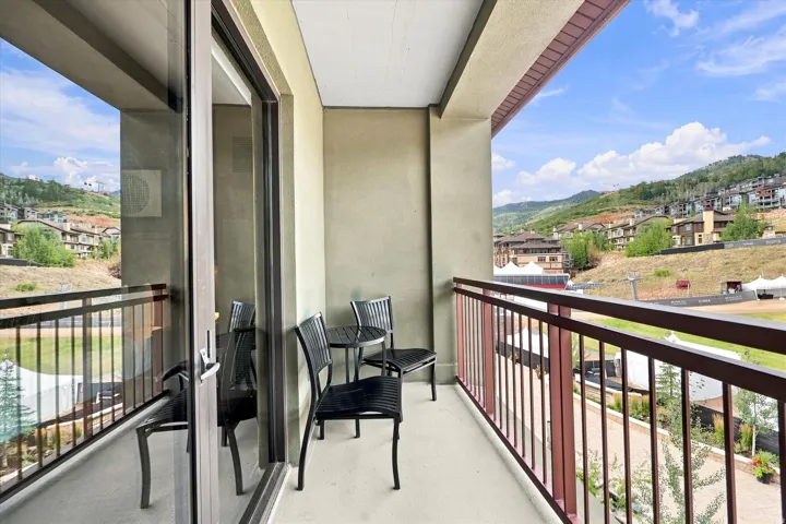 Private balcony with a metal railing, overlooking distant hills and residential structures
