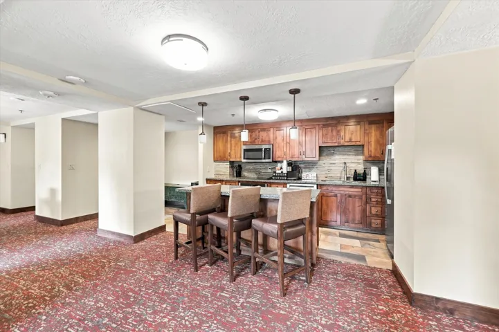 Kitchen featuring wood cabinetry, stainless steel microwave, and pendant lighting over a breakfast bar