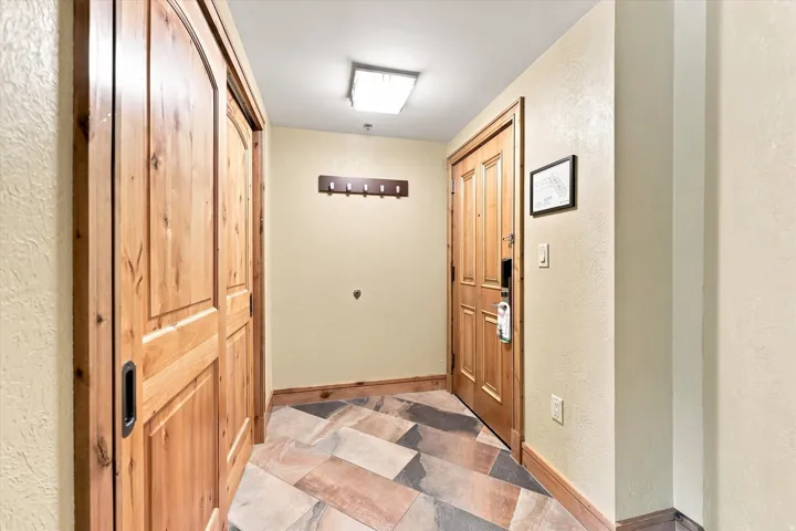 Entryway featuring wood-finish flooring, a paneled wood entry door, and a built-in coat rack