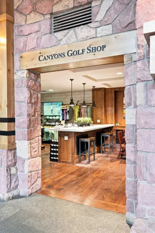 Stone-clad entryway with a wood beam accent, wood-finish flooring, and a built-in island with seating