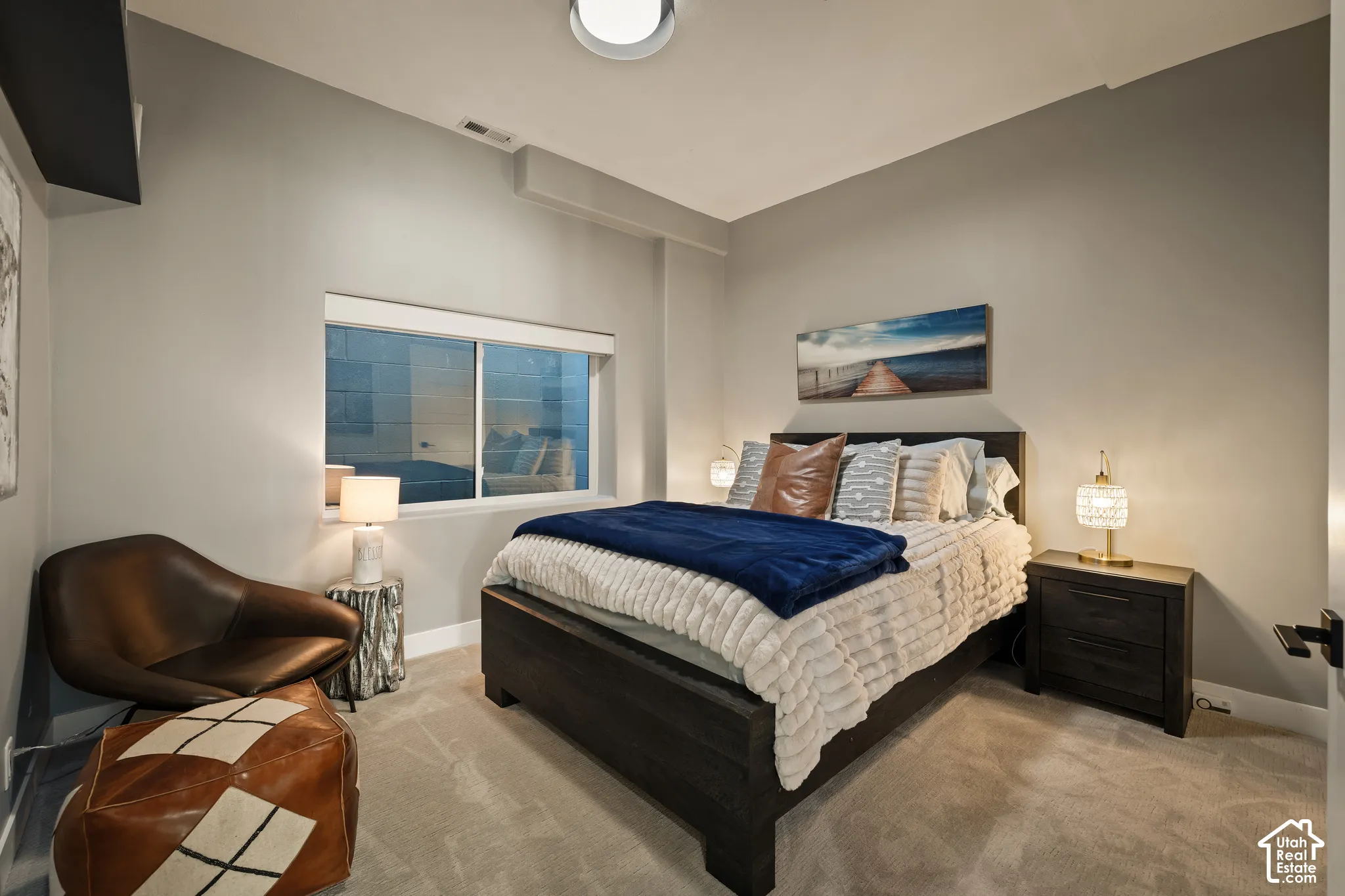 Carpeted room featuring a window with a white frame, a dark wood-finish bed frame, and a dark wood-finish nightstand