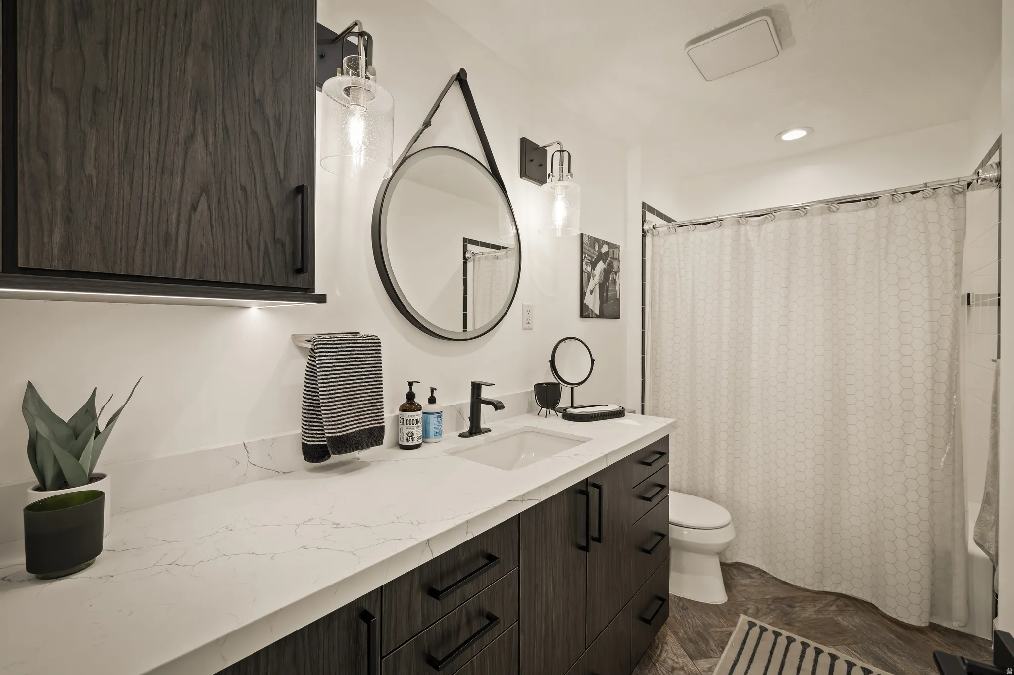 Modern vanity with a rectangular undermount sink, white countertop, and dark wood-finish cabinetry