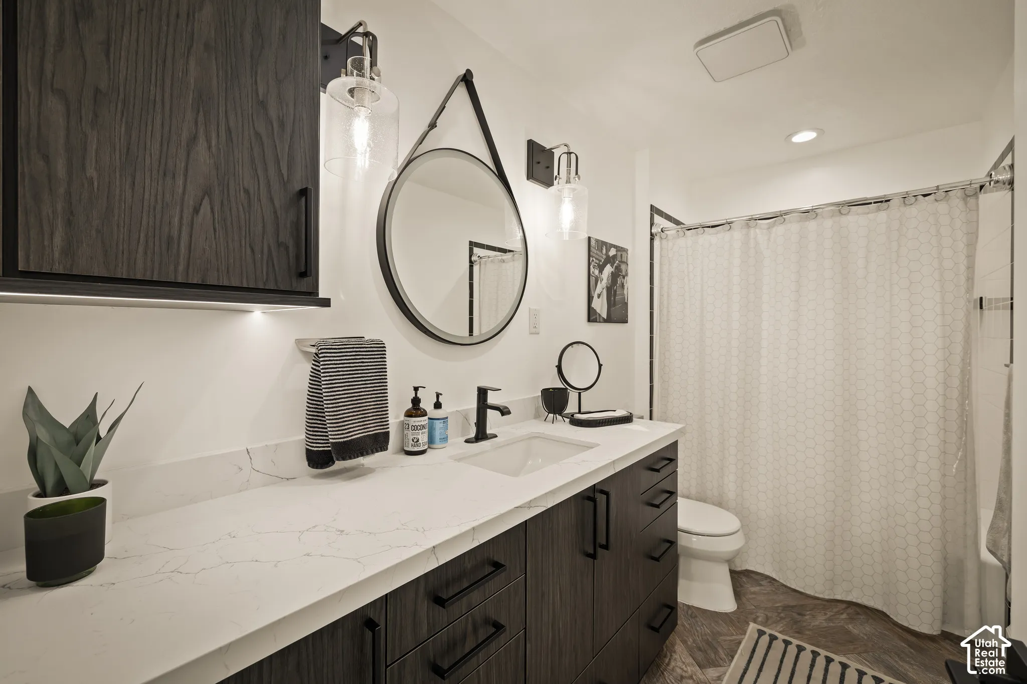 Modern vanity with a rectangular undermount sink, white countertop, and dark wood-finish cabinetry