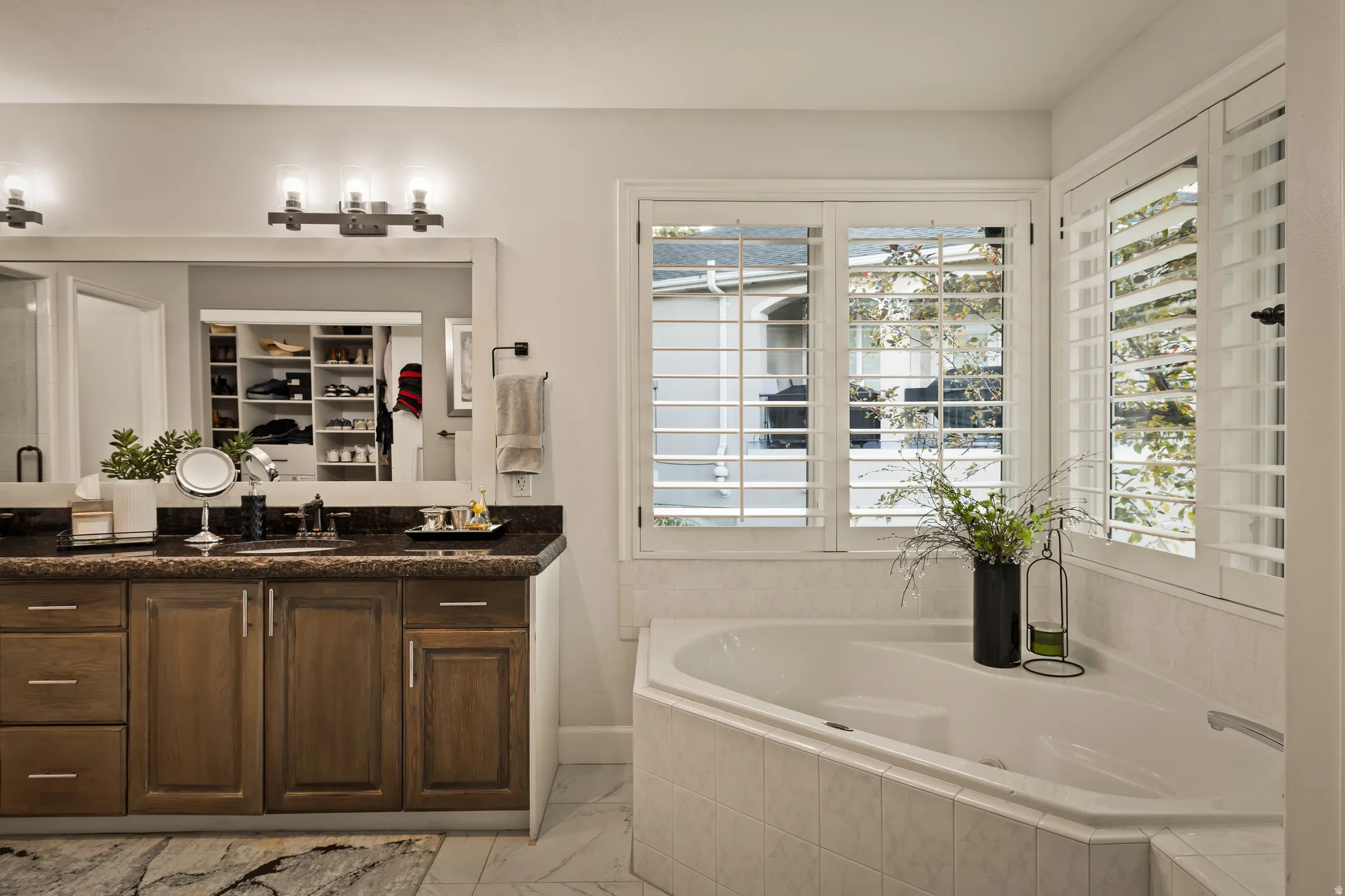 Dual vanity with dark stone countertop, undermount sinks, and wood-finish cabinetry